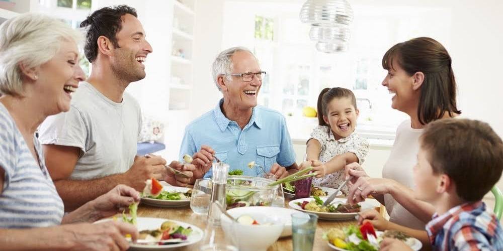 Multi Generation Family Eating Meal Around Kitchen Table